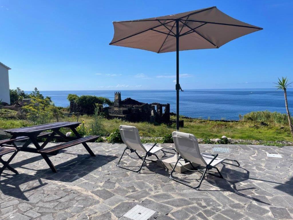 - une table de pique-nique, 2 chaises et un parasol dans l'établissement Casa Cachalote - Ferienhaus auf den Azoren, à São Caetano