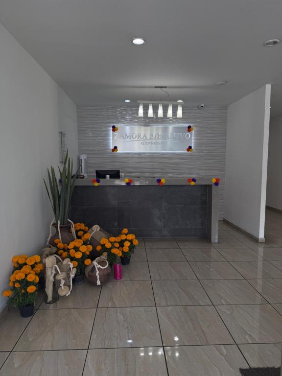 サモラ・デ・イダルゴにあるZAMORA EJECUTIVO EXPRESSのオレンジと花が飾られたカウンターのあるロビー
