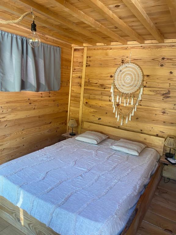 ein Schlafzimmer mit einem Bett in einer Blockhütte in der Unterkunft Le nid de l Eyrieux in Saint-Martin-de-Valamas