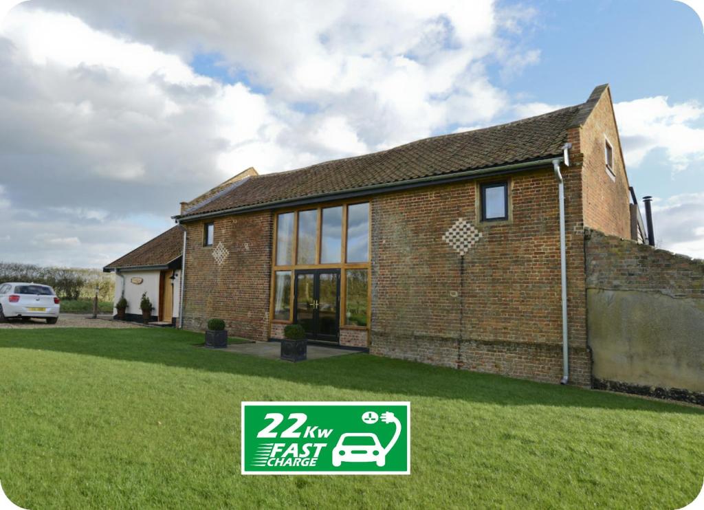 a brick house with a sign in front of it at Old Field Barn Luxury B&B in Attleborough