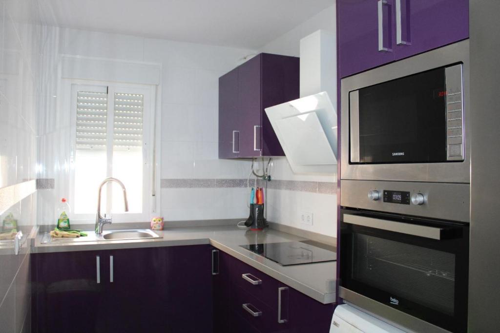 a kitchen with purple cabinets and a sink and a microwave at Grey House in Huelva