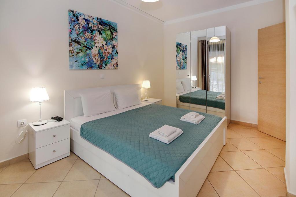 a white bedroom with a bed and a mirror at Maisonette Allegro in Ormos Panagias
