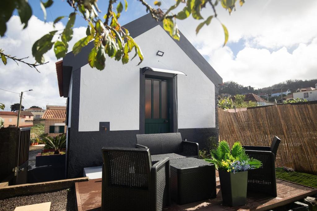 a small white house with a green door and chairs at Casa Serafina by Rent-a-key in Santa Maria Madalena