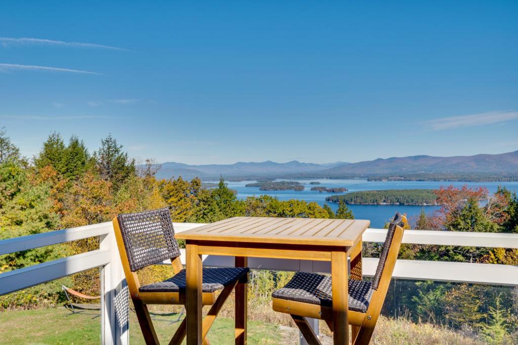 a wooden table and chairs on a fence with a view of the water at Million-Dollar Mtn Views! Gilford Gilded Loon in Glendale