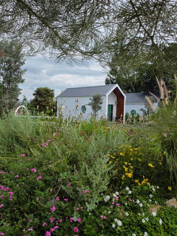 een bloemenveld met een huis op de achtergrond bij Wind in the Wild Khao Yai in Nakhon Ratchasima