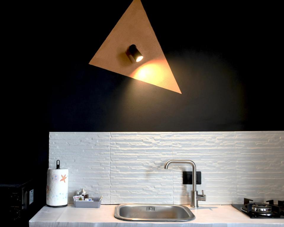 Eine dreieckige Wandleuchte über der Küchenspüle in der Unterkunft Appartamenti "UNIQUE" palazzo storico FAENZA in Faenza