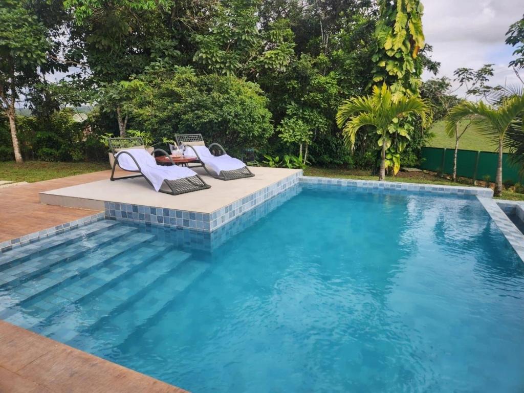 a woman laying in lounge chairs next to a swimming pool at Exclusive Huts in Gravatá