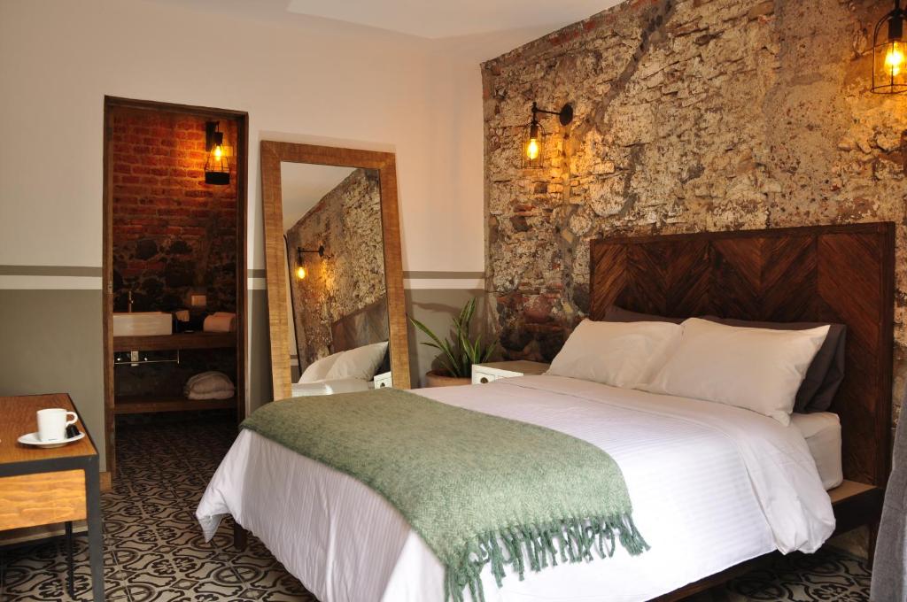 1 dormitorio con 1 cama grande y pared de piedra en Clandestino Hotel - Adults Only, en San Miguel de Allende
