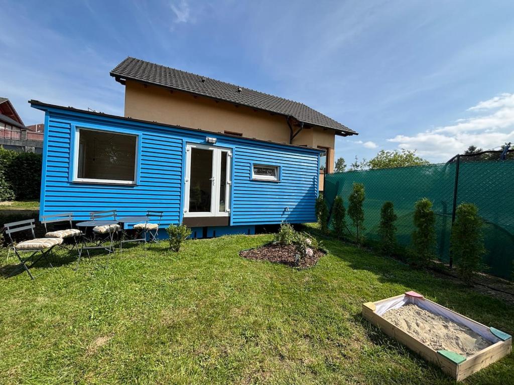 a blue tiny house in a yard next to a fence at Celoročně obyvatelná maringotka Kratochvíle 