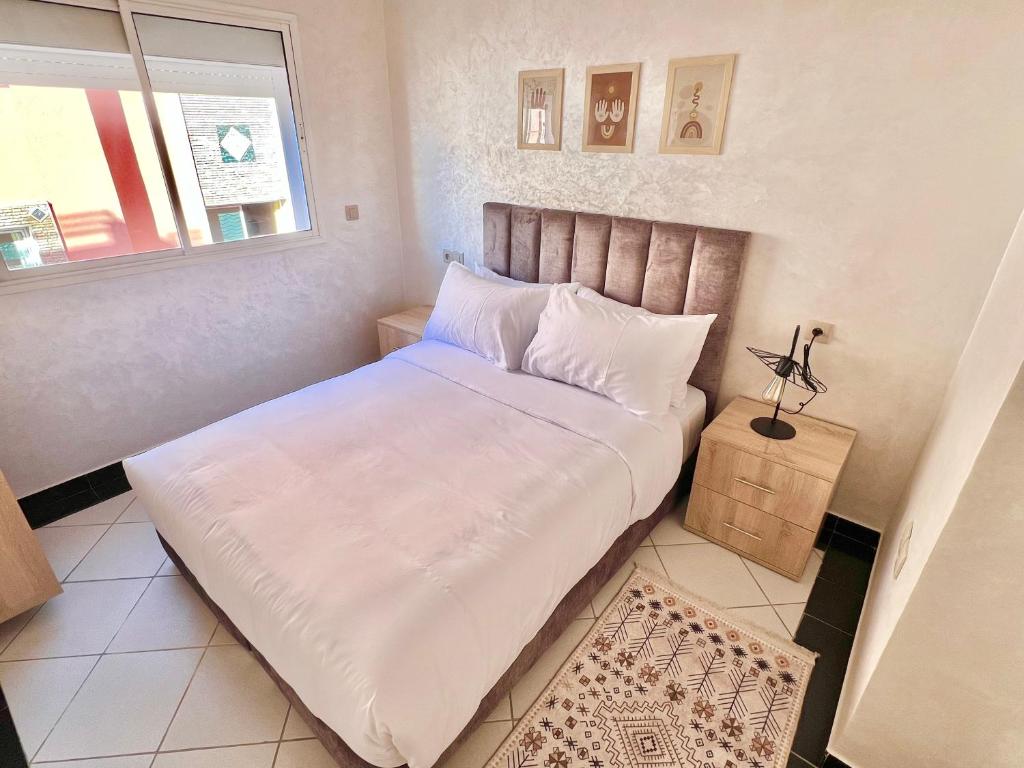 a small bedroom with a bed with white sheets and a window at A12 Studio cosy Tamraght Idéal nomades & surfers in Tamraght Ouzdar