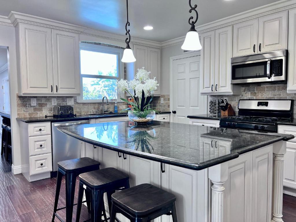 a kitchen with white cabinets and a large island with stools at Destination #22 in Anaheim
