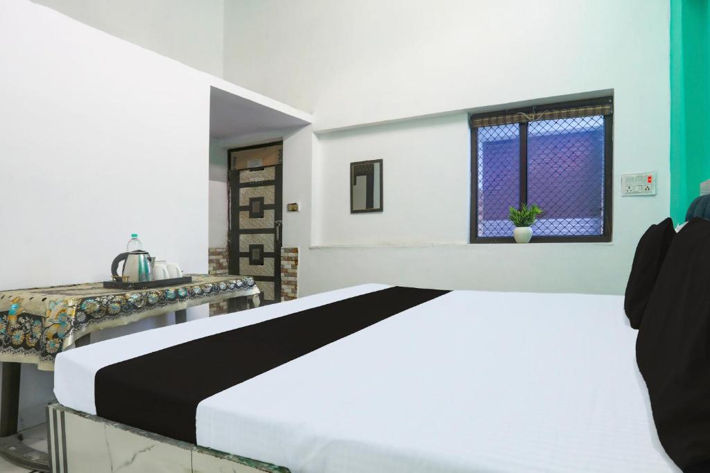 een slaapkamer met een bed, een tafel en een raam bij Hotel O SAMRAT HOTEL in Aligarh