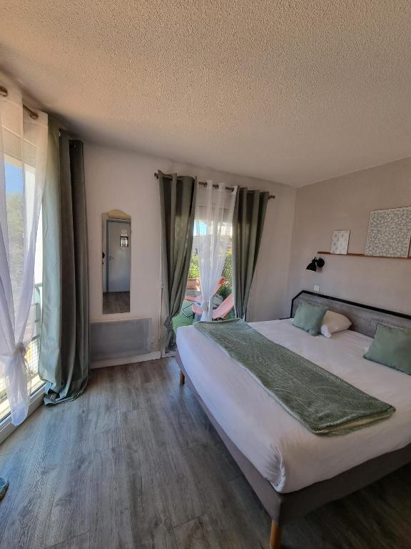 a bedroom with a large bed and large windows at Amadour Hôtel in Rocamadour
