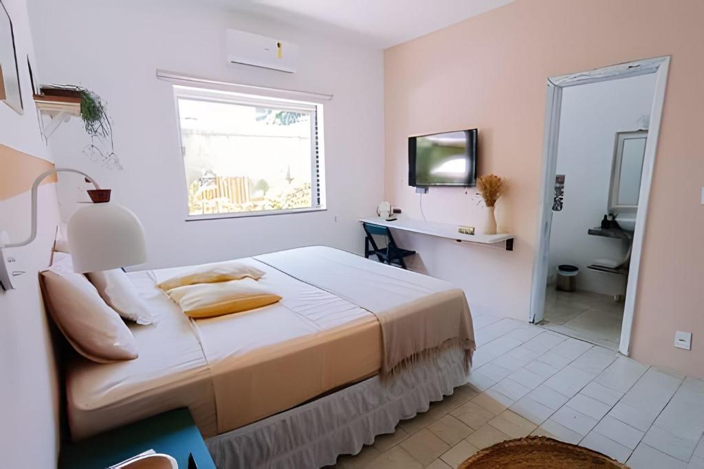 a white bedroom with a bed and a window at CASA MANGARITO in Ubatuba