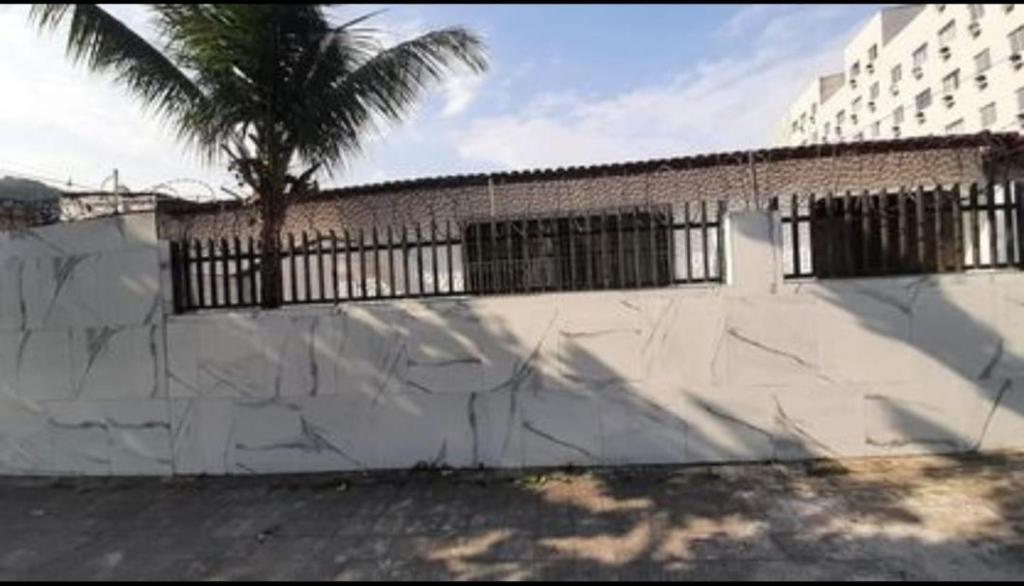 a white wall with a palm tree in front of a building at Cantinho Charmoso no Guarujá in Guarujá