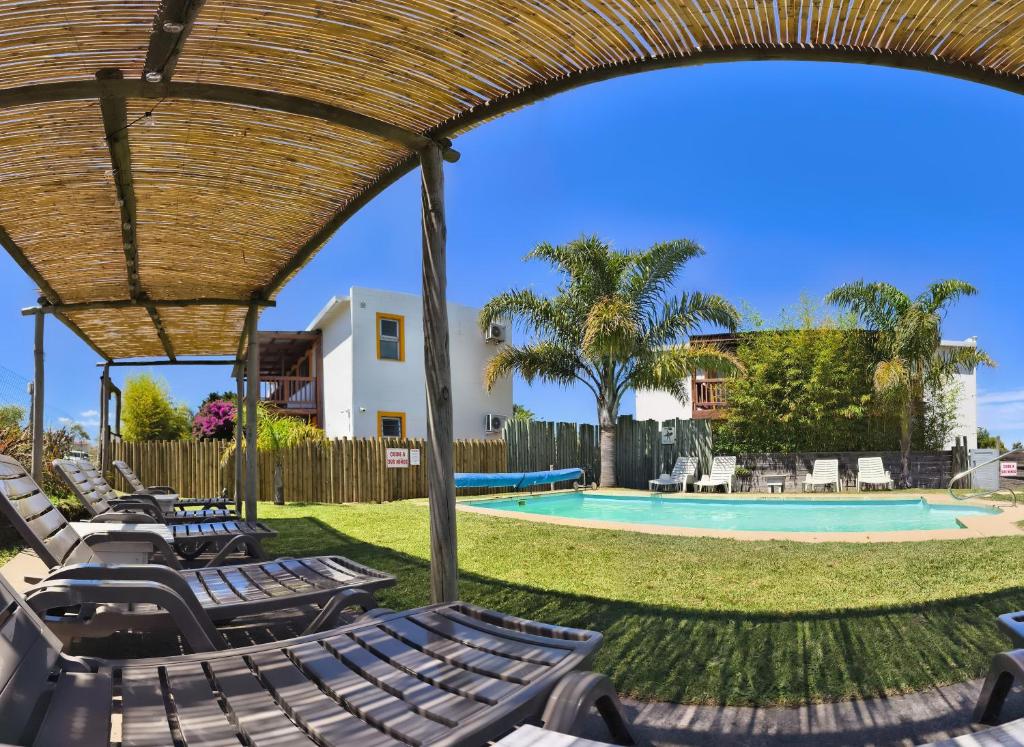 a group of lounge chairs next to a swimming pool at Apartamentos La Playa in Piriápolis