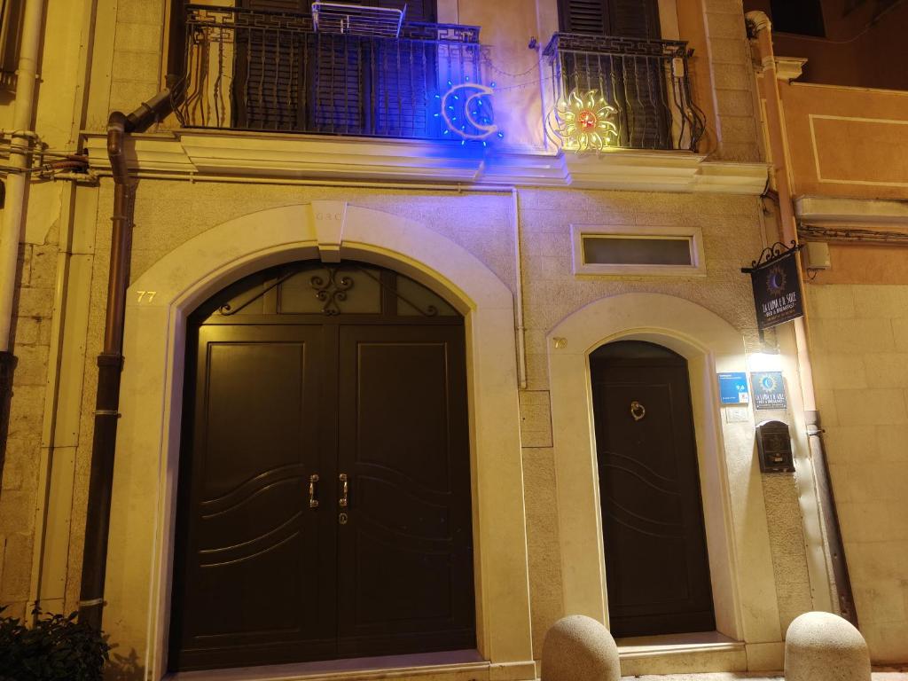 a building with two black doors and a balcony at La Luna e il Sole in Barletta