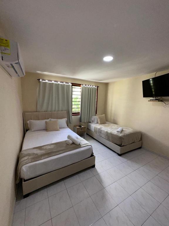 ein Schlafzimmer mit zwei Betten und einem Flachbildfernseher in der Unterkunft Hotel ladymar cartagena in Cartagena de Indias