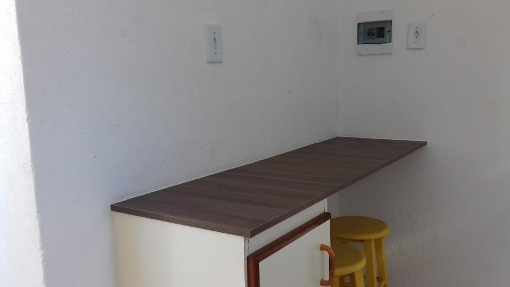 a kitchen with a counter and a yellow stool at Kitinete na praia do Mar Grosso Mobiliada in Laguna