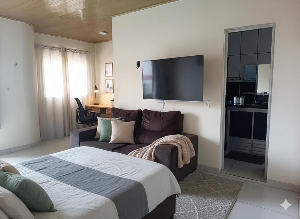 een slaapkamer met een bed, een bank en een flatscreen-tv bij Casa da família Neri - 130 in Belém