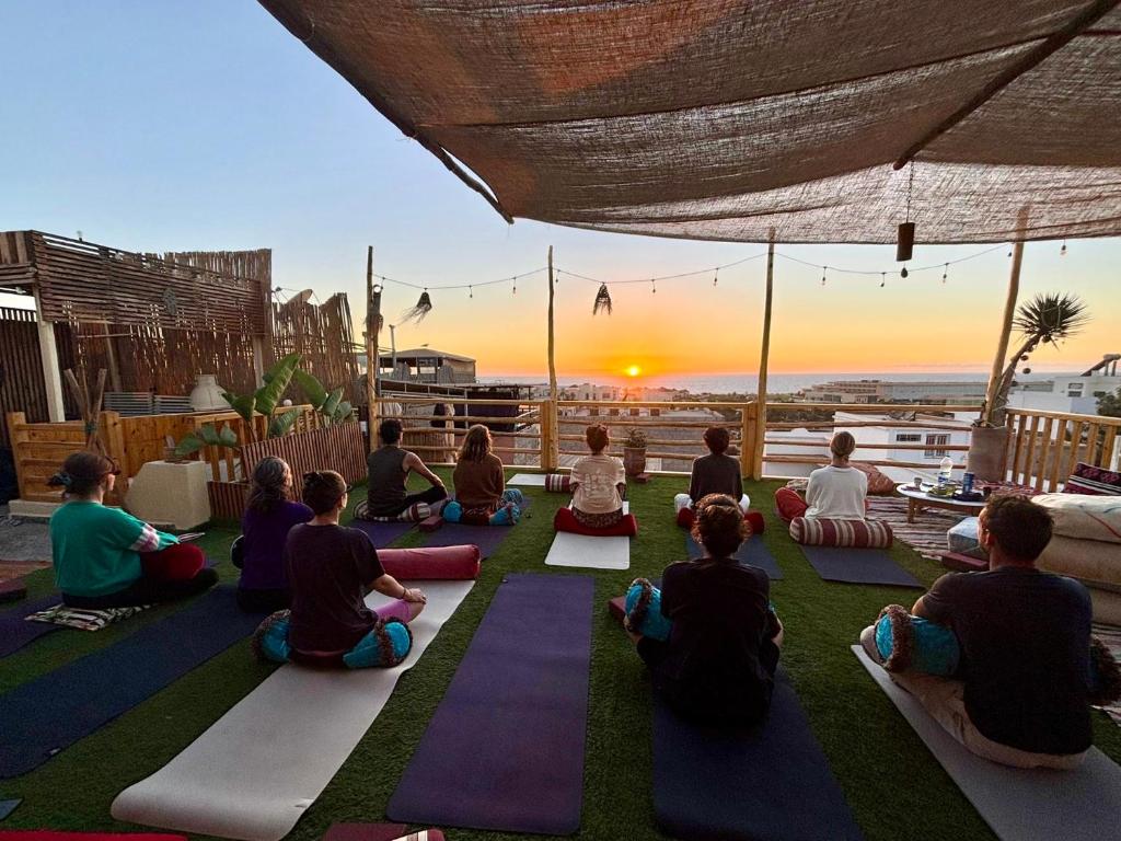 a group of people sitting on the ground in a yoga class at Natural Surf House in Tamraght Ouzdar