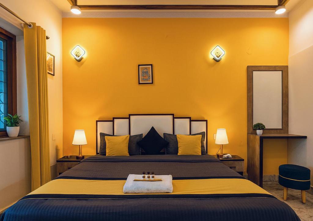 a bedroom with a large bed with yellow walls at Hidden Leaf in Dehradun