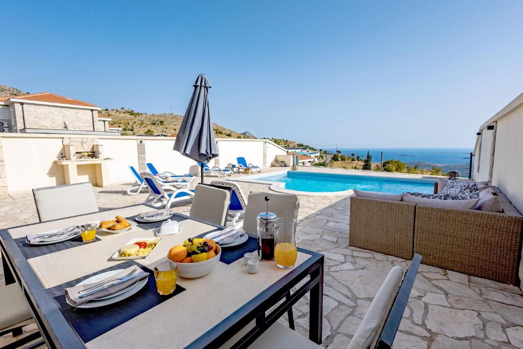 a table with food on it next to a pool at Luxury Villa Layla with private pool near Dubrovnik in Ivanica
