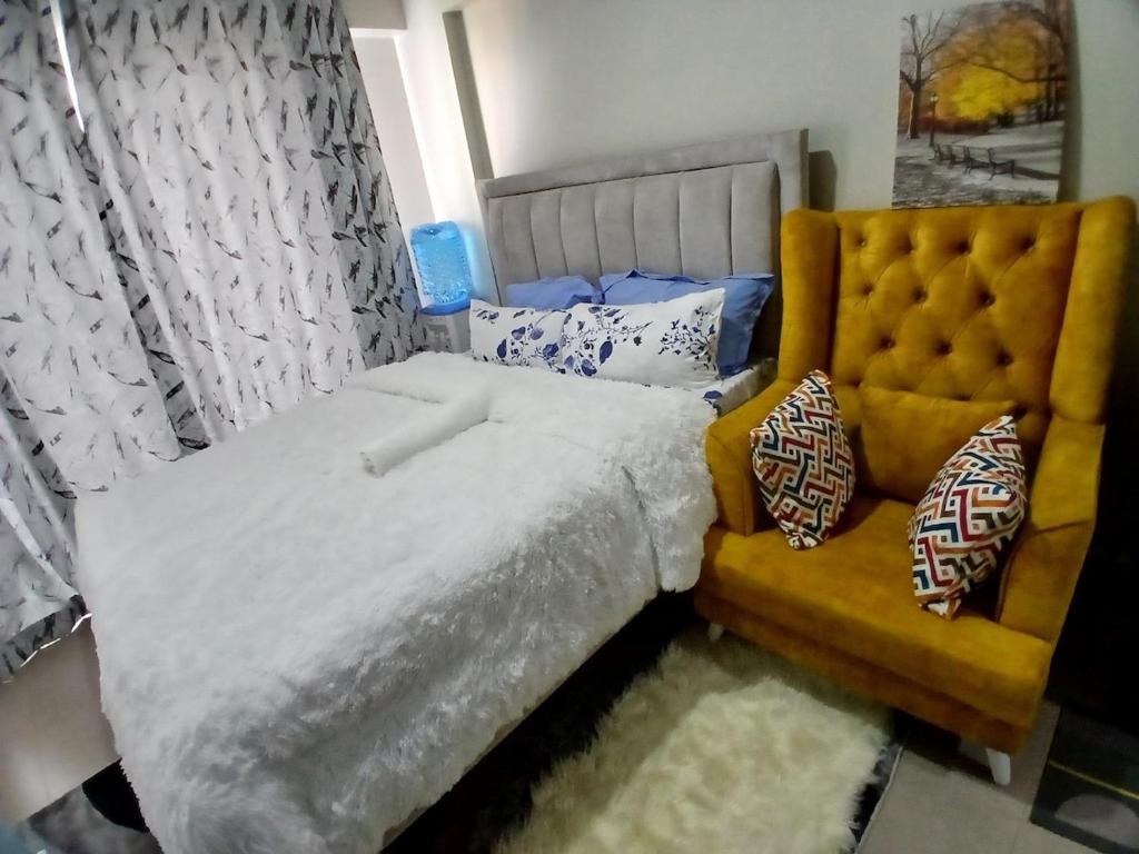 a bedroom with a large bed and a yellow chair at Akb Home Nyayo Studio in Nairobi