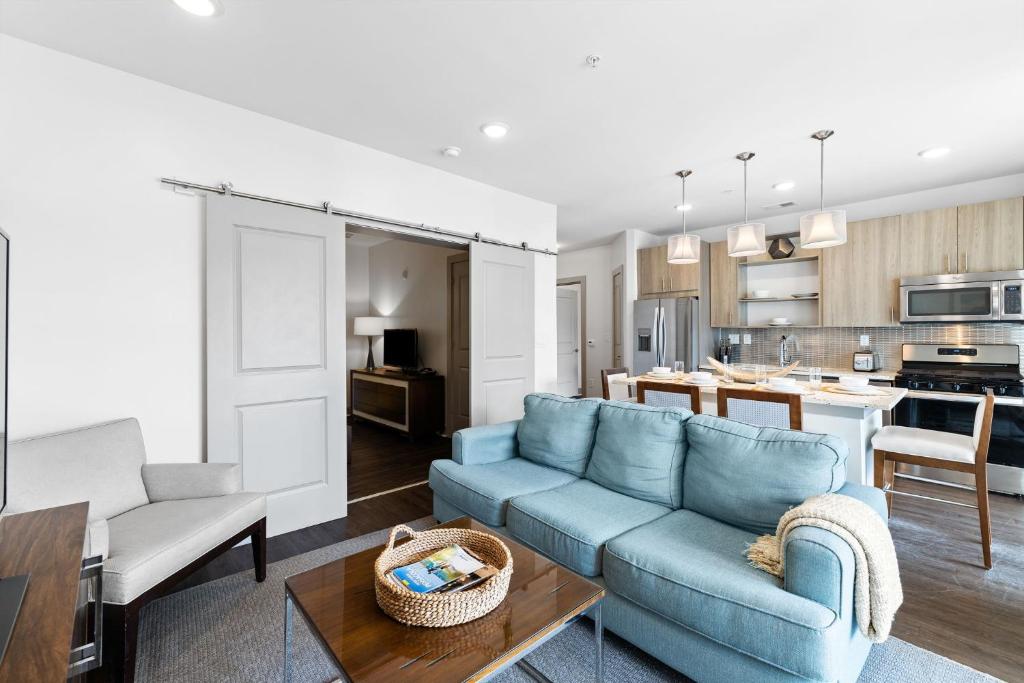 a living room with a blue couch and a kitchen at Texas Two Step by 30A Escapes in Rosemary Beach