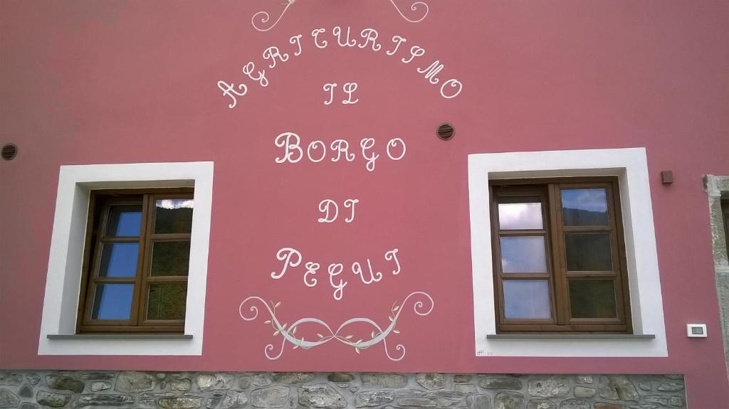 um edifício cor-de-rosa com uma placa na lateral. em Il Borgo Di Pegui em Bolano