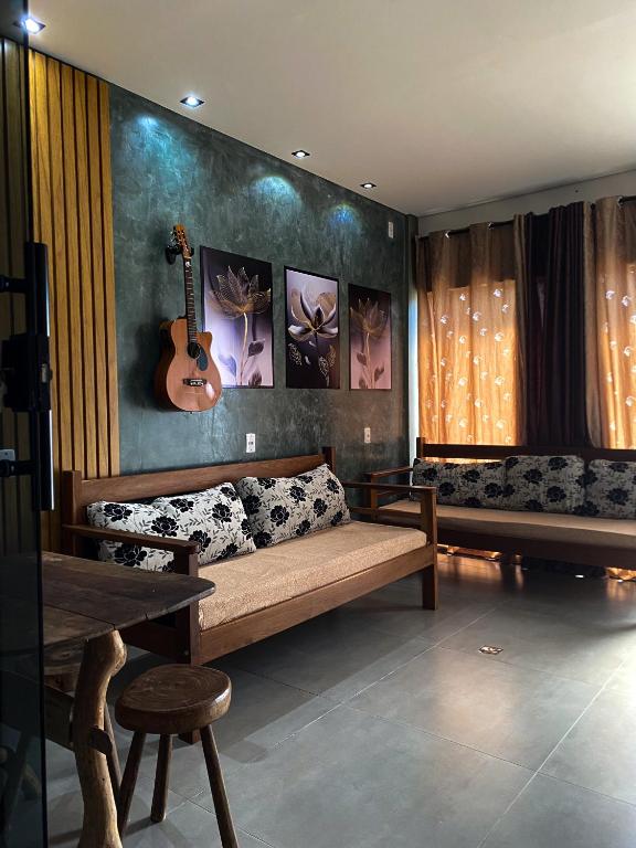 a living room with a couch and a guitar on the wall at Amoras flat in Sao Jorge