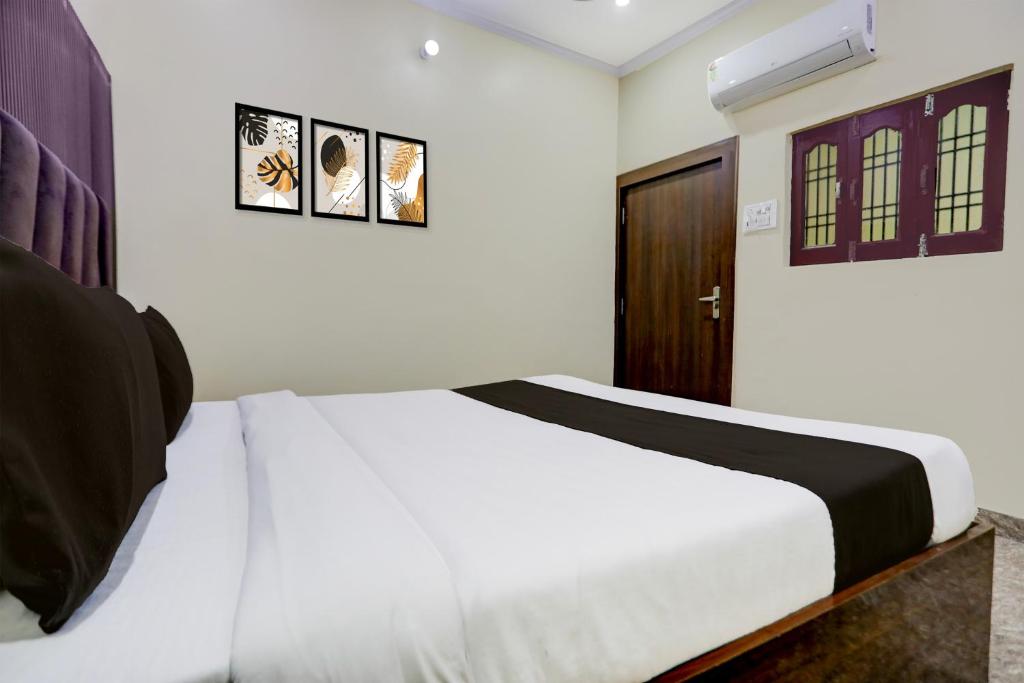 a bedroom with a white bed and a wooden door at Hotel O Kanha Paying Guest House in Varanasi