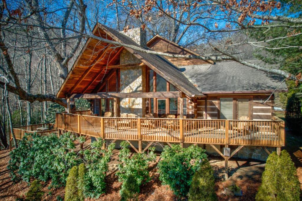 a log cabin with a large deck in the woods at Fox's Lair in Sugar Grove
