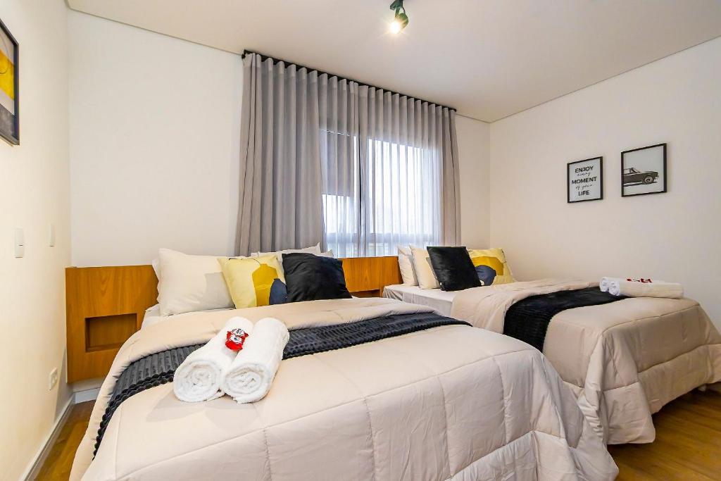 a bedroom with two beds with towels on them at Studio com 2 Camas de Casal e Garagem - EIX0705 in Curitiba