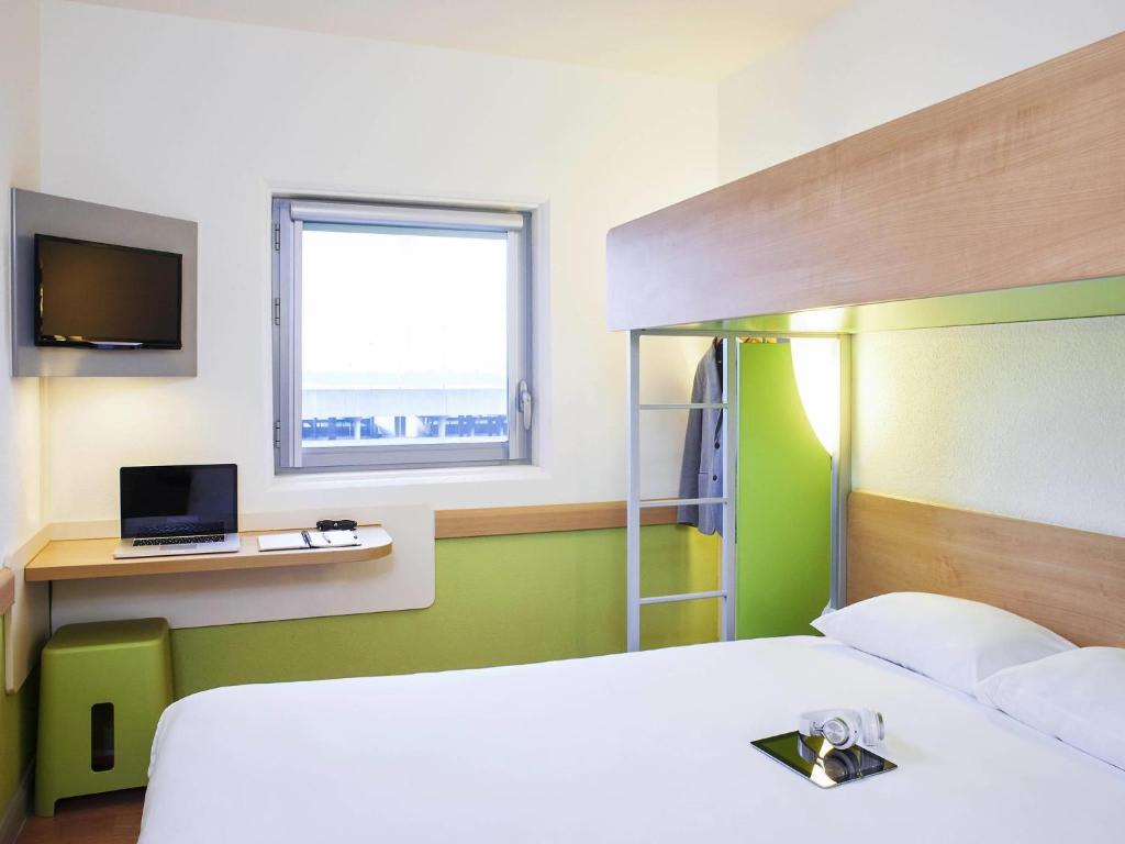 a bedroom with a bed and a desk with a laptop at ibis budget Birmingham Airport Terminal Building - NEC in Bickenhill