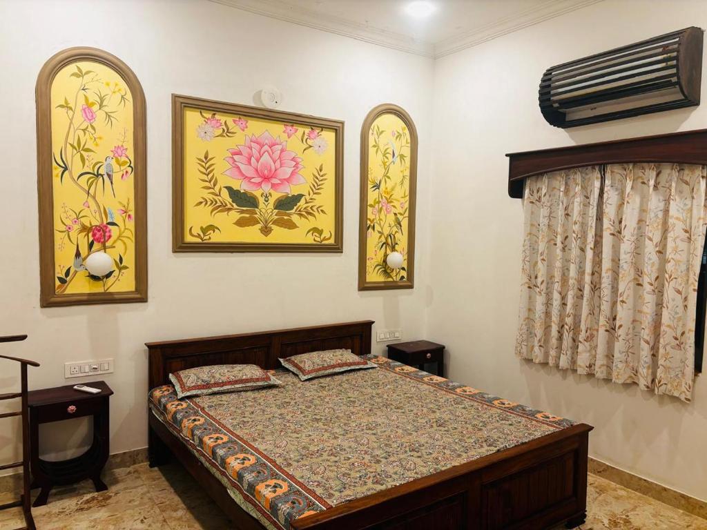 a bedroom with a bed and two pictures on the wall at Sajjan Niwas - A Luxury Homestay in Jodhpur