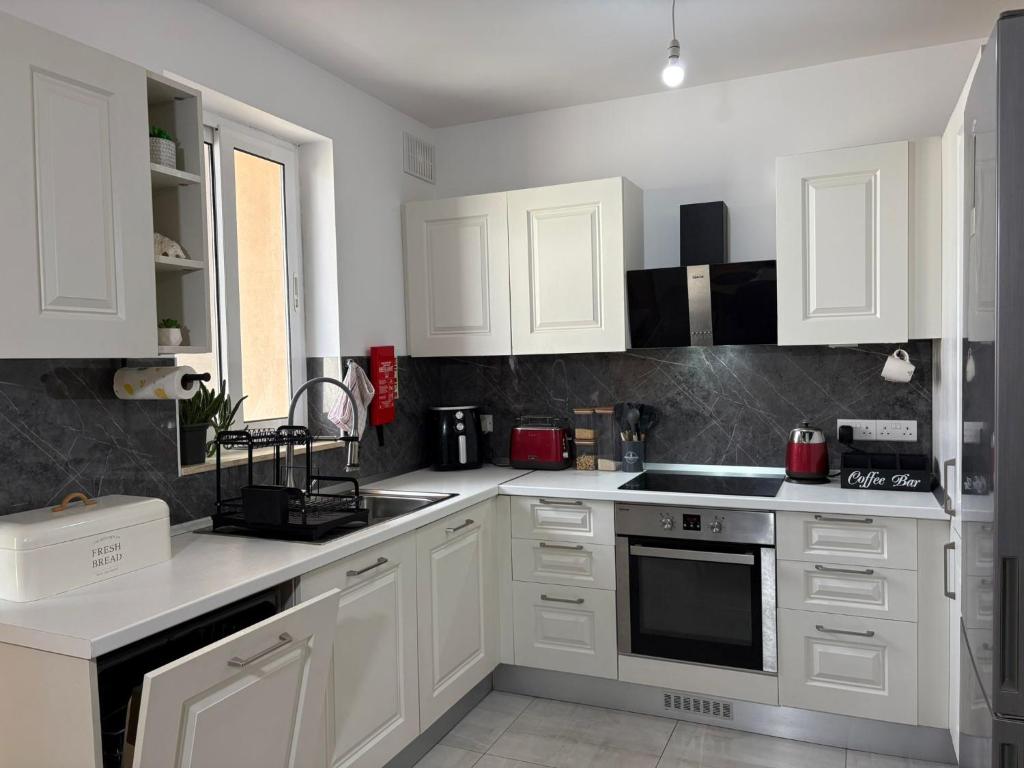 a white kitchen with white cabinets and appliances at Modern one bedroom Apartment in Żurrieq