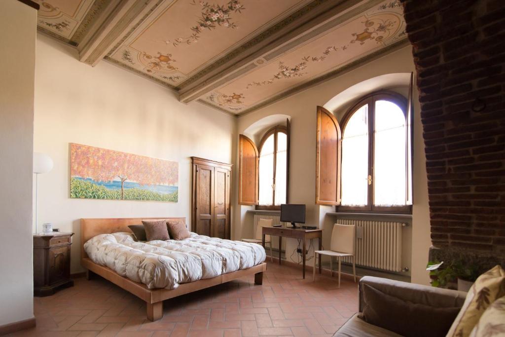 Un dormitorio con una cama y un escritorio y dos ventanas. en Suite King- La Corte del Re Suite Rooms, en Arezzo
