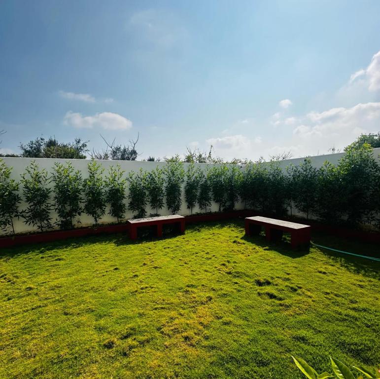 a garden with two benches in the grass at SK INN stays in Mahabalipuram