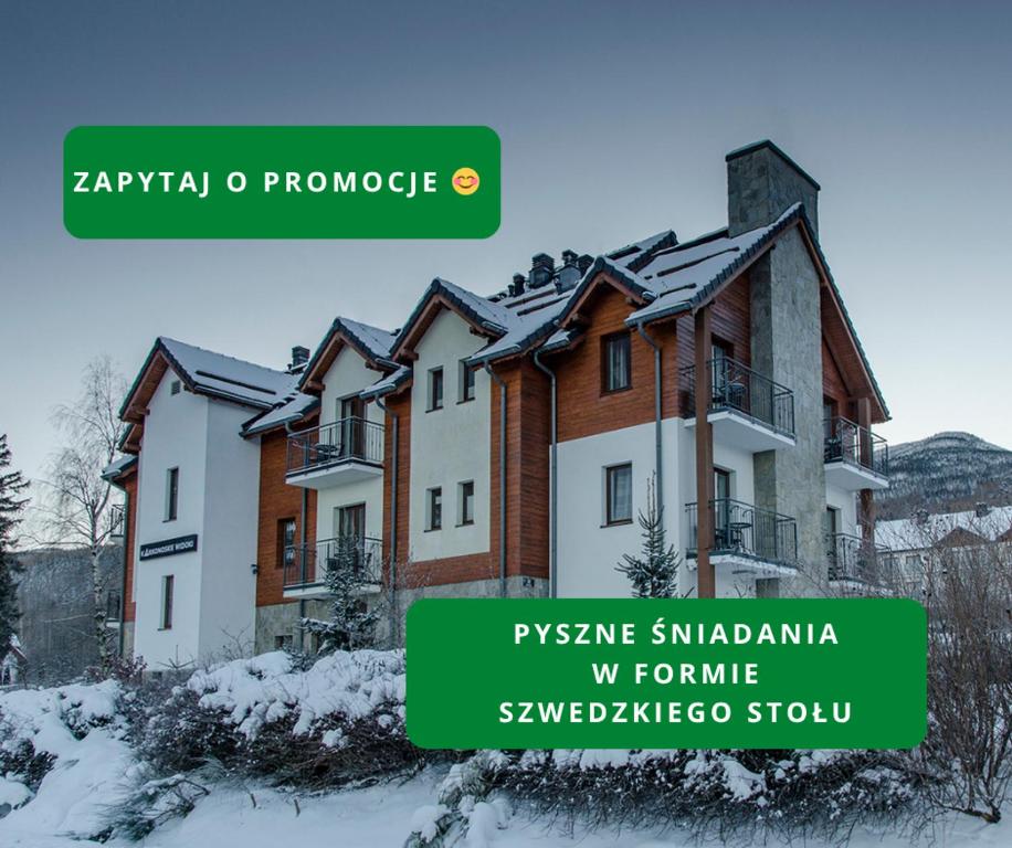 a building with snow on the ground in front of it at Karkonoskie Widoki in Karpacz