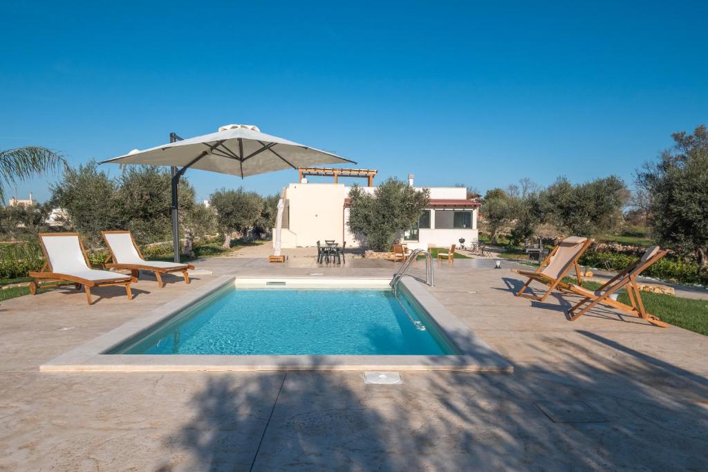 a swimming pool with chairs and an umbrella at Villa Corbezzolo in Galatone