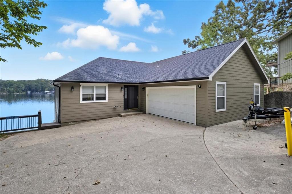 een klein huis met garage naast een meer bij Expansive Deck, Beautiful Views, Private Dock & Boat Slip in Sunrise Beach