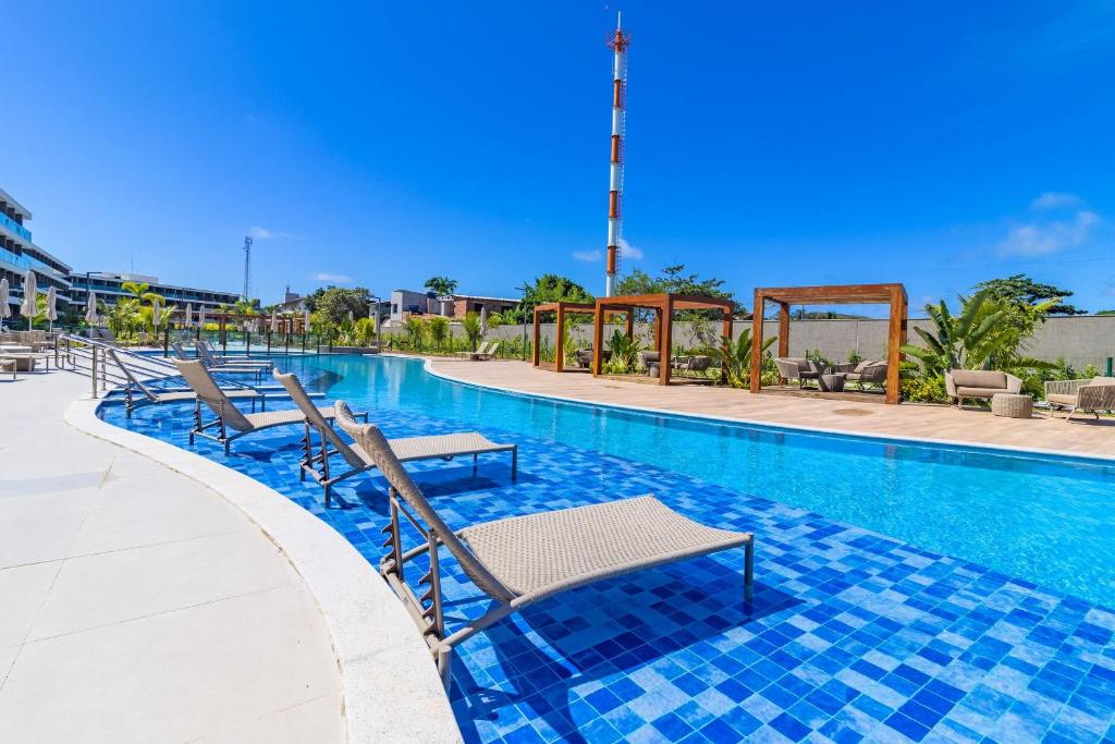 a swimming pool with chaise lounges and chairs at Beach Class Summer resort condominium by Carpediem in Porto De Galinhas