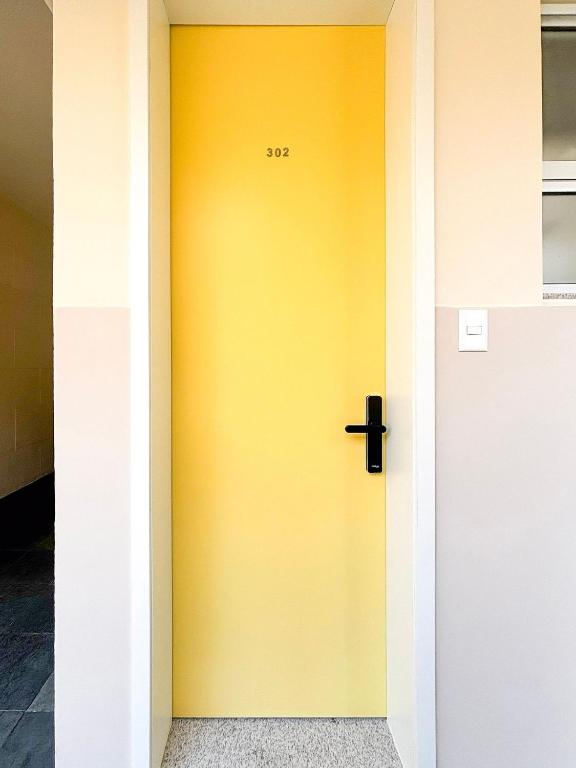 a yellow door with a black cross on it at Estúdio na melhor rua do Leblon in Rio de Janeiro