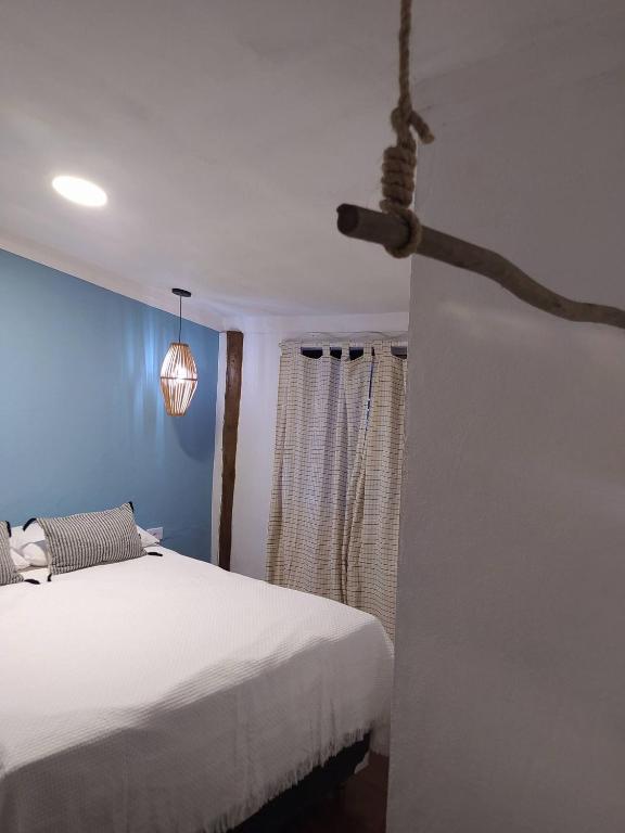 a bedroom with a white bed and a blue wall at Casa Tupi - suítes no coração do Itaguá em Ubatuba in Ubatuba