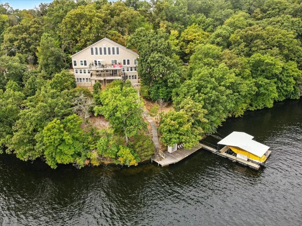 een groot huis op een eiland in het water bij Lakefront Home w/ Double Deck, Slip, Firepit & Game Room in Sunrise Beach