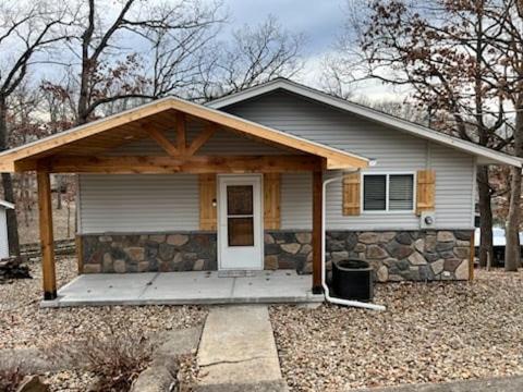 ein kleines weißes Haus mit einer Steinmauer in der Unterkunft Stunning Views of the 75mm, Private Dock, Spacious Decks, Kayaks & More! in Buck Creek