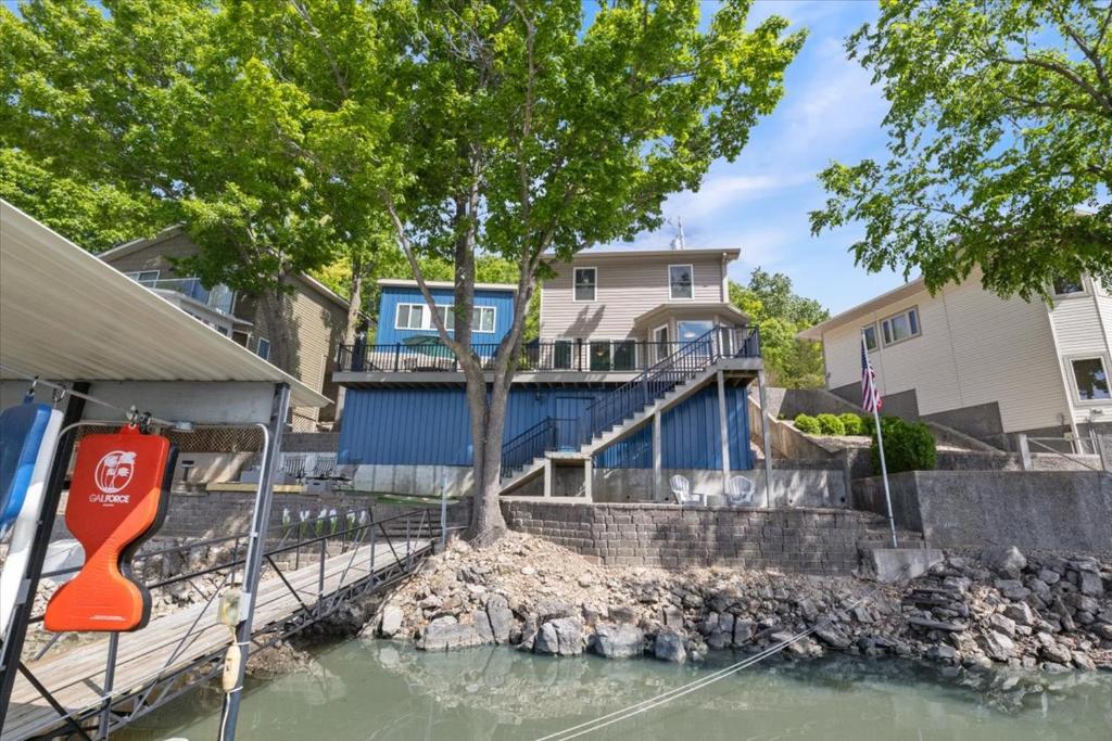 a house on the water with a tree in front at Private Dock, Bunkhouse, Firepit & Kayaks at MM45 in Laurie