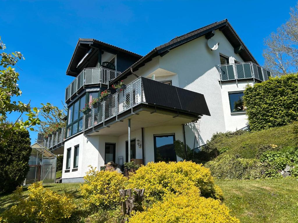 a white house with a balcony on a hill at Ferienwohnung Moos-Hochsauerland in Wiemeringhausen