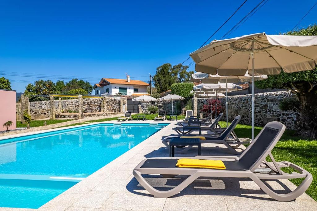 a swimming pool with lounge chairs and an umbrella at Private Villa T8 - Casa Da Bra Viana Do Castelo in Viana do Castelo